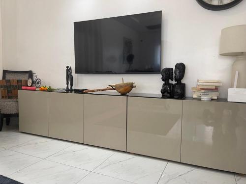 a living room with a large tv on the wall at Villa Piagne Bastos in Yaoundé