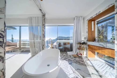 La salle de bains est pourvue d'une baignoire blanche et d'une grande fenêtre. dans l'établissement Villa de luxe avec vue panoramique sur la mer et Monaco, à Roquebrune-Cap-Martin