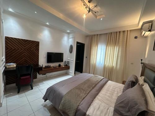 a bedroom with a bed and a desk and a television at Villa Piagne Bastos in Yaoundé