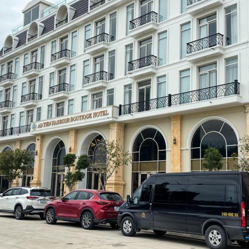 two cars parked in front of a large building at Ao Tien Harbour Boutique Hotel in Hà Cái