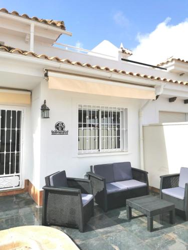 a patio with chairs and tables in front of a house at Gregorys Poolside Villa in Sucina