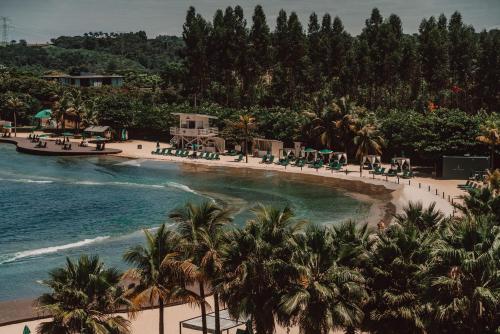 a view of a beach with palm trees and the ocean at Boa Vista Surf Lodge in Pôrto Feliz