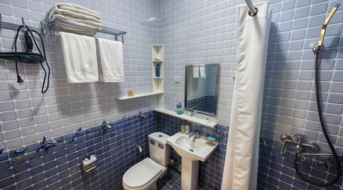 a blue tiled bathroom with a toilet and a sink at Квартира-галерея в центре города in Dushanbe