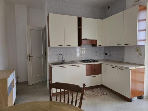 Savito Guest House mare في توري كان: مطبخ بدولاب بيضاء وطاولة ومغسلة