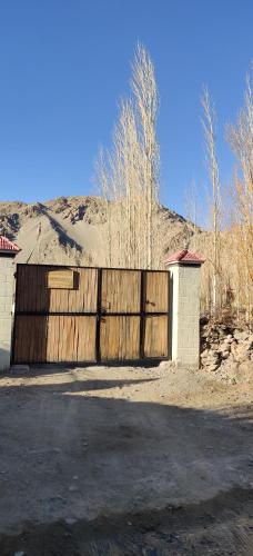 a wooden fence with a gate in front of a mountain at Devaranya Homestay in Leh