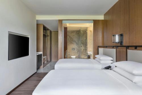 a hotel room with two beds and a flat screen tv at Jim Corbett Marriott Resort & Spa in Rāmnagar