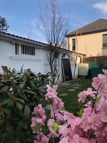 une cour avec des fleurs roses devant une maison dans l'établissement Chez Emma, à Beauchamp