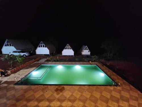 a swimming pool in front of a house at night at Nirved Retreat Resort - A Backwater Forest Peaceful Stay in Bhor, Pune in Āpti