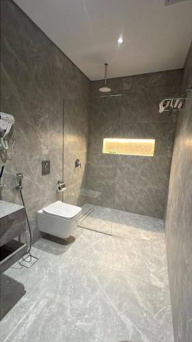 a bathroom with a toilet and a glass shower at الشاطئ الأبيض للشقق المخدومة in Rabigh