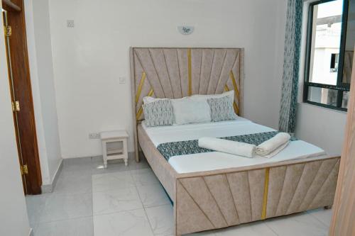 a bed with a wooden headboard in a room at Kheyre Nyali Ocean View Two Bedrooms Apartments in Mombasa