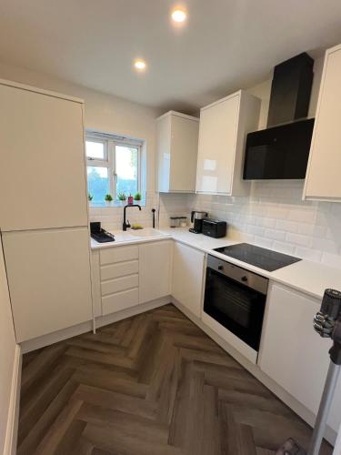 a kitchen with white cabinets and a stove top oven at Salvation View 2 Bed Apartment in Hadleigh