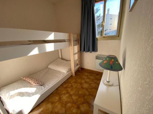 Cette petite chambre comprend des lits superposés et une lampe. dans l'établissement Appartement Port Hyères 2 ch terrasses box, à Hyères