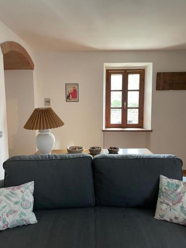 a living room with a blue couch and a lamp at Typical house in Trebbia Valley in Cella