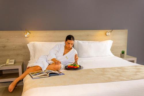 a woman sitting on a bed with a plate of fruit at VVC Hotel's in Villavicencio