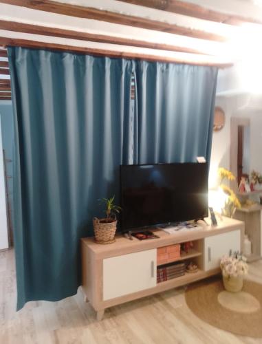 a living room with a television and blue curtains at Apartamento Turístico El Empedrado de M&G in Colmenar de Oreja