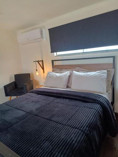a bedroom with a blue and white bed with a chair at loft charmoso com lareira, a beira mar in Balneário Gaivotas