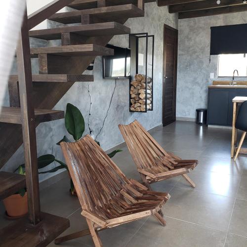 two wooden chairs in a room with a spiral staircase at loft charmoso com lareira, a beira mar in Balneário Gaivotas