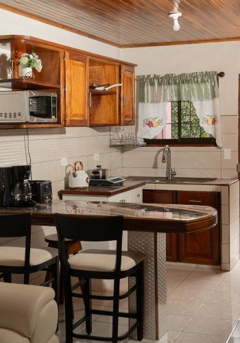 a kitchen with wooden cabinets and a counter with bar stools at Departamento Ángeles del Arenal #1 in Fortuna