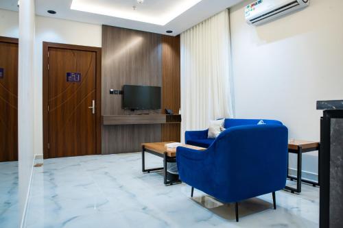 a living room with a blue chair and a tv at فندق فجر الواحة in Riyadh