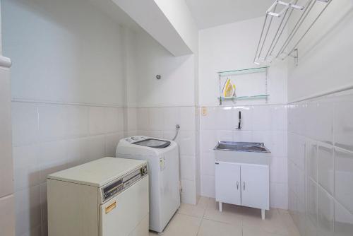 a white bathroom with a sink and a washer at ITNC191 - Vista mar incrível do alto do 19º andar in Balneário Camboriú