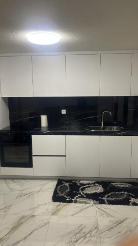 a kitchen with white cabinets and a sink at Arbesi Apartament in Gjilan