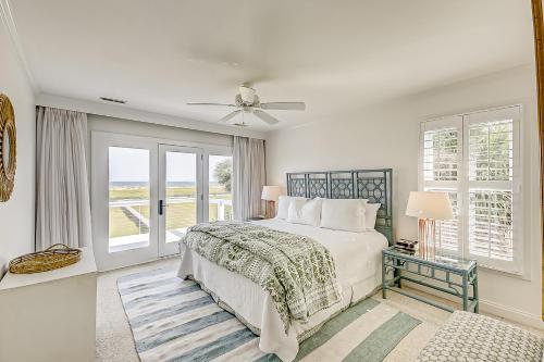 a white bedroom with a bed and a window at Luna Sea in Edisto Beach