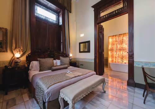 a bedroom with a bed with a bench and a window at La Casa del Centro, Mérida in Mérida
