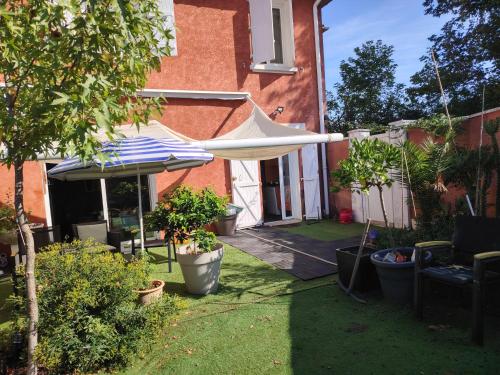 a patio with an umbrella and some potted plants at Chambre Suite Zen Baignoire sous les toits in Bénesse-Maremne