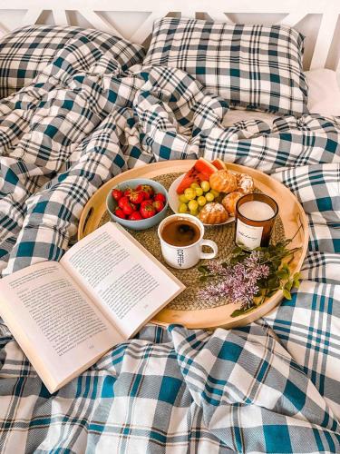 a plate of food on a bed with a book at Rajska Cisza - całoroczny prywatny domek w lesie nad jeziorem - sauna i balia in Krąg
