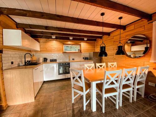 a kitchen with a table and some white chairs at Rajska Cisza - całoroczny prywatny domek w lesie nad jeziorem - sauna i balia in Krąg