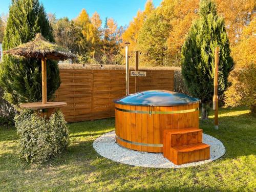 a wooden hot tub with a bench and an umbrella at Rajska Cisza - całoroczny prywatny domek w lesie nad jeziorem - sauna i balia in Krąg