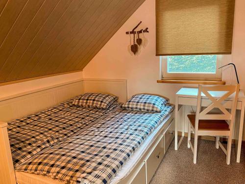 a bed with two pillows in a room with a desk at Rajska Cisza - całoroczny prywatny domek w lesie nad jeziorem - sauna i balia in Krąg