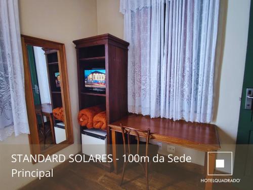 a room with a mirror and a cabinet with a television at Hotel Quadrado in Santa Bárbara