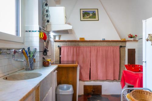 a kitchen with a sink and a red shower curtain at Grazioso appartamento in campagna a Procchio in Marciana