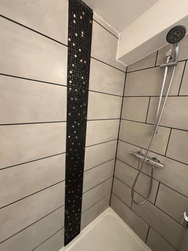 a shower with a black and white tile wall at La Volcane - Quiet house in Le Chesnay
