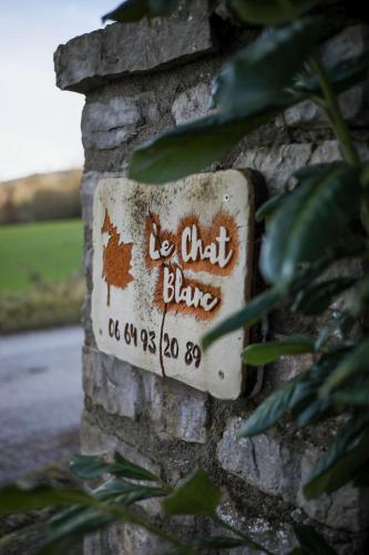 a sign on the side of a brick wall at Le Chat Blanc Gîte in Versols-et-Lapeyre