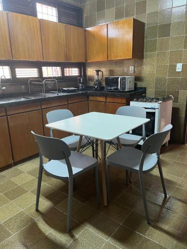 a kitchen with a white table and chairs in it at Studio Sal - 3 min do Mossoró Cidade Junina in Mossoró
