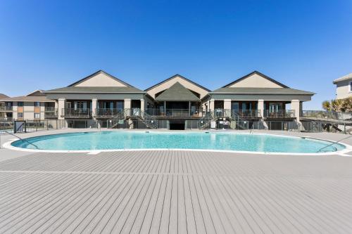 a large swimming pool in front of a house at Oceanview 4BR/4BA Condo, Steps to Beach/Pool in Ocean Isle Beach