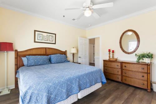 a bedroom with a blue bed and a mirror at Oceanview 4BR/4BA Condo, Steps to Beach/Pool in Ocean Isle Beach