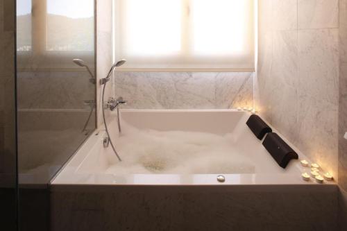 a white bath tub with a shower and a window at Mas Vivent in Vilamaniscle