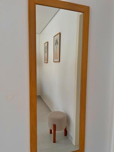 a mirror with a stool and a chair in a room at Olisa Praia Hotel in Maresias