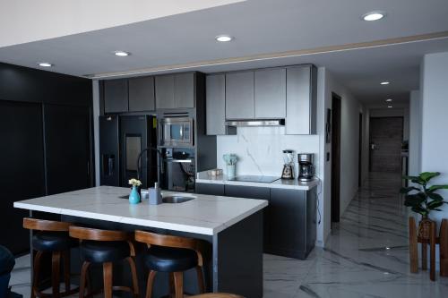 a kitchen with black cabinets and a island with bar stools at Mazatlán departamento por malecon in Mazatlán