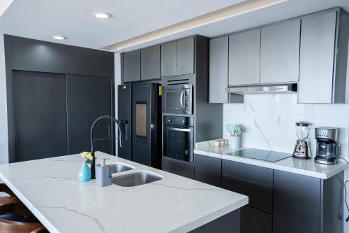a kitchen with black cabinets and a white counter top at Mazatlán departamento por malecon in Mazatlán
