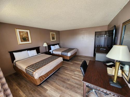 a hotel room with two beds and a desk at Satellite Inn in Alamogordo