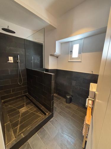a bathroom with a shower with black tile at Apt Es Poal - Des Puig in Cadaqués
