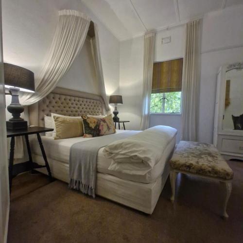 a bedroom with a white bed and a window at Simondium's Country Lodge in Simondium