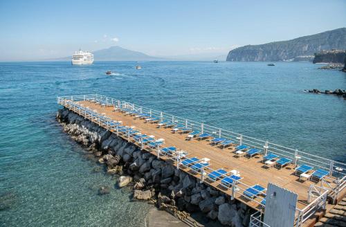 a pier with chairs and a cruise ship in the water at Grand Hotel Europa Palace Sorrento in Sorrento