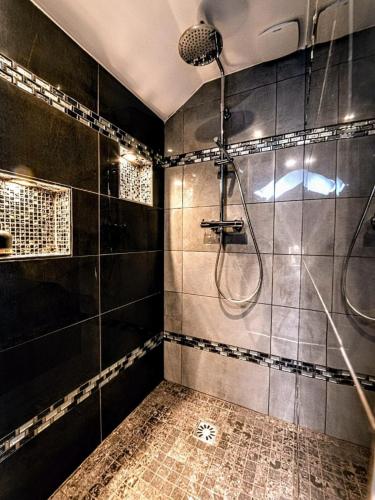 La salle de bains est pourvue d'une douche avec du carrelage noir. dans l'établissement La Petite Escapade, maison avec jacuzzi privatif, à Héricy