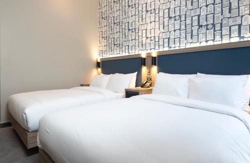 two beds in a hotel room with white sheets at Brit Hotels Earls Court in London