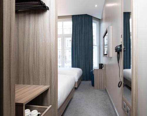 a hotel room with a bed and a window at Brit Hotels Earls Court in London